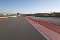 the race track is empty and red as the car drives past it on its way to a win