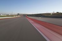 the race track is empty and red as the car drives past it on its way to a win