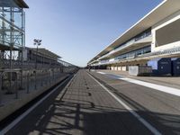 an empty track with the sun reflecting off of the ground and the buildings in the background