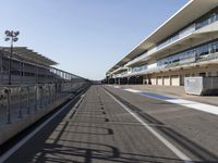 an empty track with the sun reflecting off of the ground and the buildings in the background
