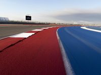 an empty race track with markings and red grass on the side of it and white squares