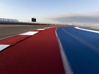 an empty race track with markings and red grass on the side of it and white squares