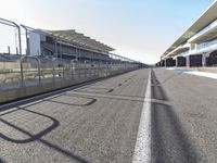 an empty race track with only a few people standing and waiting for the start to begin