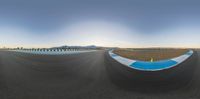 a fish eye lens captures the scenery in the background of an empty runway with a large sky overhead