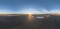 a 360 - view of an empty track and the sun setting behind it with clouds