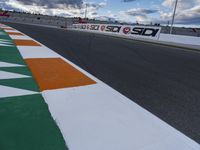 the race track is empty during a cloudy day with an orange and white paint line