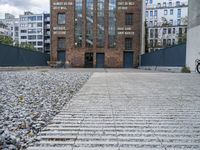 the entrance to an old red brick building is empty and covered with rock stones on a city street