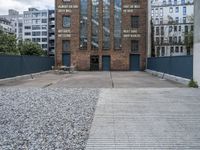 the entrance to an old red brick building is empty and covered with rock stones on a city street