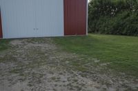 an empty red and white building is near a grassy field and two trees in the distance