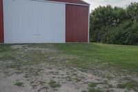 an empty red and white building is near a grassy field and two trees in the distance