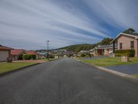 an empty residential street with many houses in the distance and mountain range in the distance