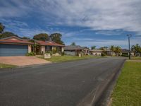 an empty residential street with a small residential area to the right, as one house looks on