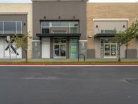 an empty retail center with shops lining the street from it to the sidewalk, a curb or street