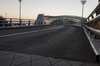 an empty road with a bridge over the street on which lights are shining off from above