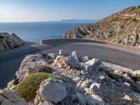 an empty road running along a cliff overlooking the water and ocean with rocks in the foreground