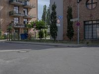 an empty road is lined with apartment buildings in the background and on either side there is a street sign with trees