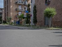 an empty road is lined with apartment buildings in the background and on either side there is a street sign with trees