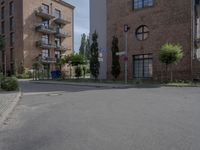 an empty road is lined with apartment buildings in the background and on either side there is a street sign with trees