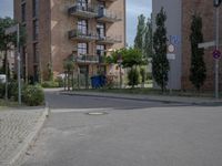 an empty road is lined with apartment buildings in the background and on either side there is a street sign with trees