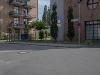 an empty road is lined with apartment buildings in the background and on either side there is a street sign with trees