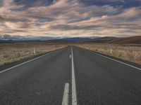 a empty road that leads towards the mountains at dusk, in an image from australia