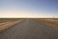 the empty open road is empty at night time near the horizon, and a single lone object is visible in the distance