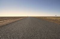 the empty open road is empty at night time near the horizon, and a single lone object is visible in the distance