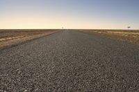 the empty open road is empty at night time near the horizon, and a single lone object is visible in the distance