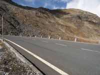 an empty highway with mountains in the background at the bottom of it and a street light