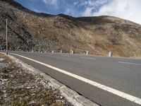 an empty highway with mountains in the background at the bottom of it and a street light