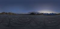 a car on an empty road and mountains in the background at night time taken in fish eye mode