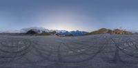 a car on an empty road and mountains in the background at night time taken in fish eye mode