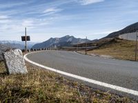 an empty road with the mountains in the back ground and rocks on the sides of the road