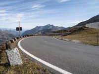 an empty road with the mountains in the back ground and rocks on the sides of the road