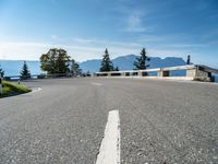 an empty road going along mountains with green bushes near by and a concrete barrier on either side