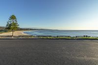 the empty road leads to a beach and a clear blue sky with no clouds on it