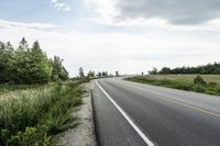 the road is empty along side the grass and trees for people to see it is empty