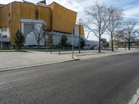 an empty road next to a building and parking lot for people on the street with one passenger vehicle