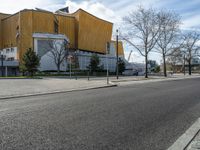 an empty road next to a building and parking lot for people on the street with one passenger vehicle