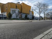 an empty road next to a building and parking lot for people on the street with one passenger vehicle