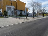 an empty road next to a building and parking lot for people on the street with one passenger vehicle