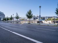 a empty road with several trees and buildings on either side of it near an intersection