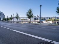 a empty road with several trees and buildings on either side of it near an intersection