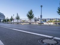 a empty road with several trees and buildings on either side of it near an intersection