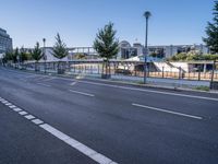 a empty road with several trees and buildings on either side of it near an intersection