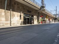 an empty road with no cars on the side of it under a bridge with a bridge to both sides