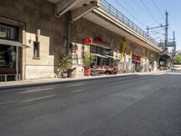 an empty road with no cars on the side of it under a bridge with a bridge to both sides