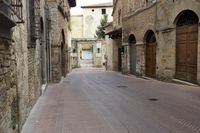 an empty road with brick buildings on either side and people walking on the other side