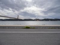 the road is empty in front of the bridge and the water is calm and empty