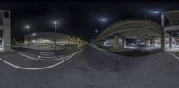 a wide angle panoramic shot shows empty road under bridge at night time,